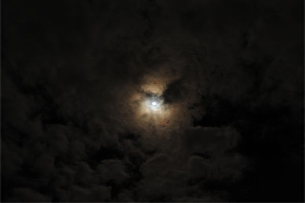 Full Moon at midnight through thin storm clouds us...