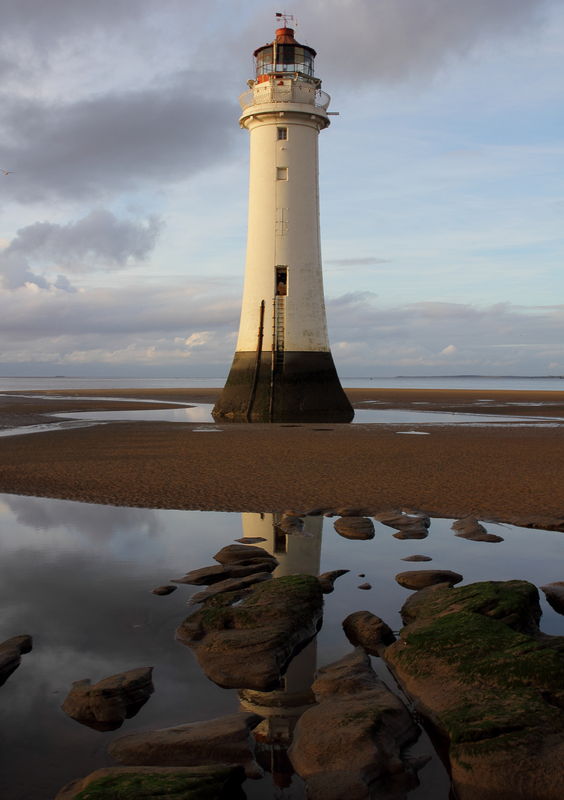 new brighton lighthouse reflection with stones red...