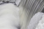 "Winter Falls", water flows over a dam on a very c...