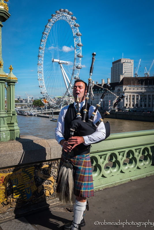 Playing a bagpipe in front of The Eye...