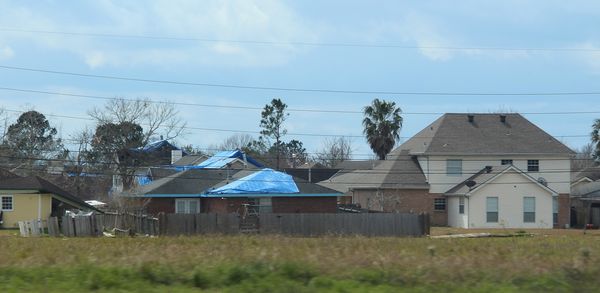 3) blue tarps on the roofs of many homes...