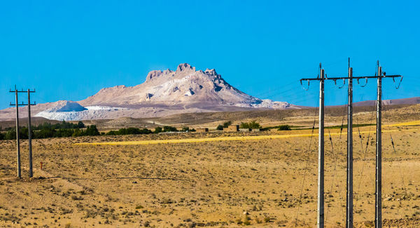 Jagged mountain framed by electricity poles...