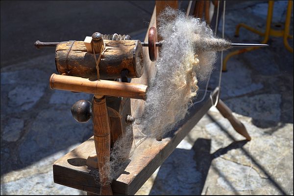 Part of an old spinning wheel showing raw wool on ...