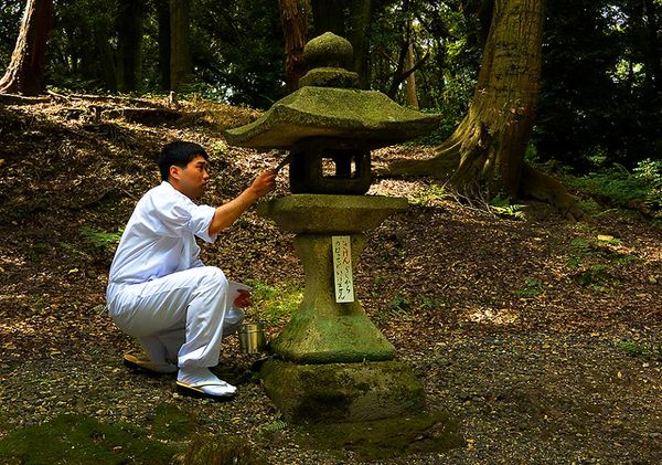 A shinto priest adding paper covers for one of the...