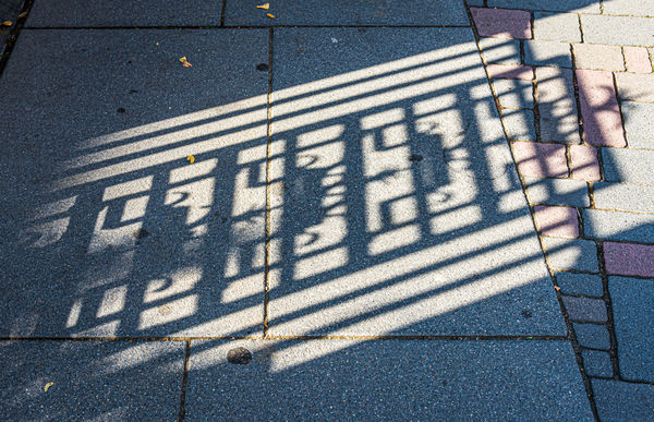 4 - Shadow pattern of a metal gate on a side walk...