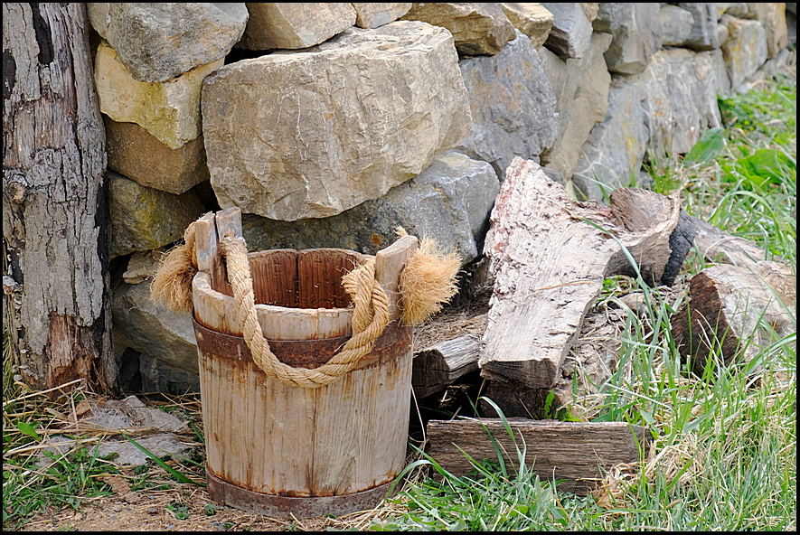8. Wooden bucket by rock wall....