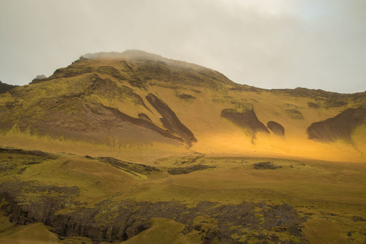 This is a mountain hillside with a fog that is lif...