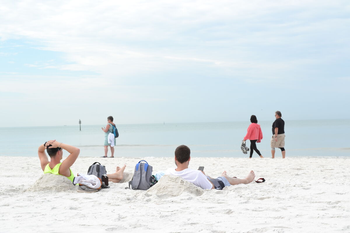 These two guys dug holes in the sand to sit so the...