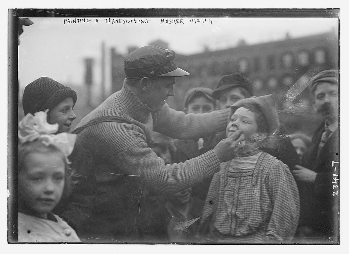 A masker gets his face painted for the 1911 parade...