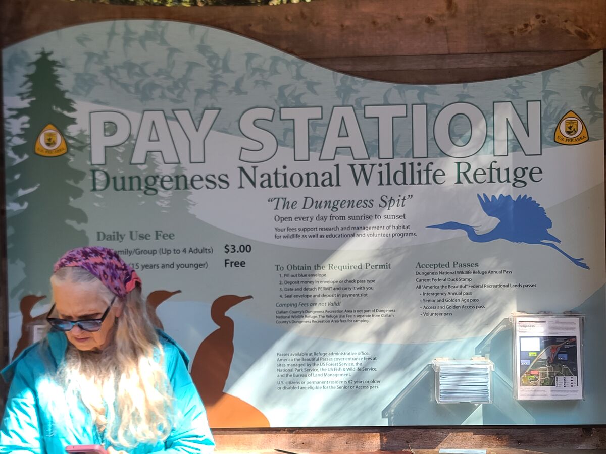 My wife in front of the sign for The Dungeness Nat...