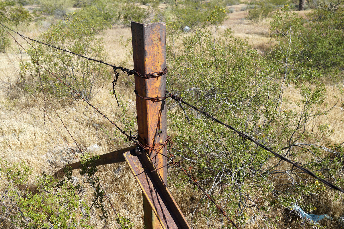 A steel fence post, with barbed wire attached, in ...